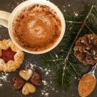Weihnachtsplätzchen, Zimt, Kakao und Tannenzapfen auf hölzernem Untergrund